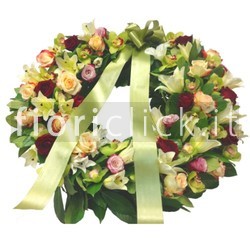 Corona funebre in armonia di colore sul verde.